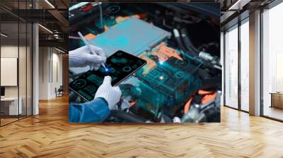 Auto mechanic using a tablet wireless scanning tool to check the ECU engine system; automobile information displayed on a screen; mechanic working on cars at a garage Wall mural